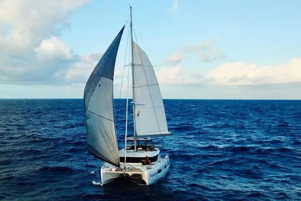 Slide: The Image of 2023 Lagoon 46 catamaran sailing on open ocean under clear blue sky. - 23