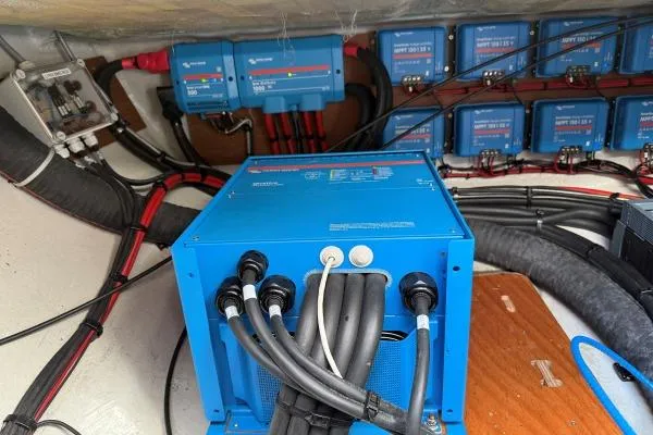 Slide: The Image of Electrical system setup in a 2023 Lagoon 46 yacht, featuring blue power units and cables. - 28