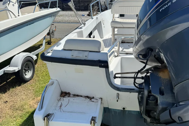 Slide: The Image of 1997 Boston Whaler Outrage 17 boat with outboard motor, parked on grass. - 7