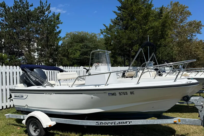 Slide: The Image of 1997 Boston Whaler Outrage 17 boat on trailer, parked outdoors near white fence. - 9