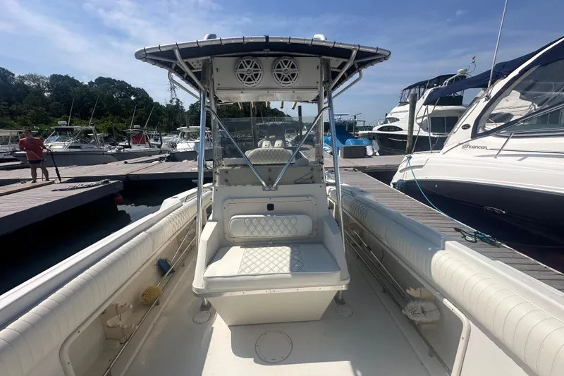 Slide: The Image of 1994 Donzi 3300 Center Console boat docked at marina, featuring spacious seating and canopy. - 8