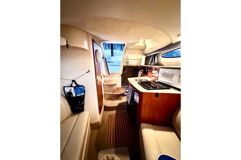Slide: The Image of Interior of 2007 Bayliner 245 Ciera boat, featuring cozy seating and compact kitchen area. - 5