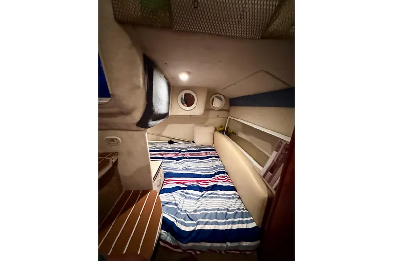 Slide: The Image of Interior cabin of 2007 Bayliner 245 Ciera with striped bedding and cozy lighting. - 7