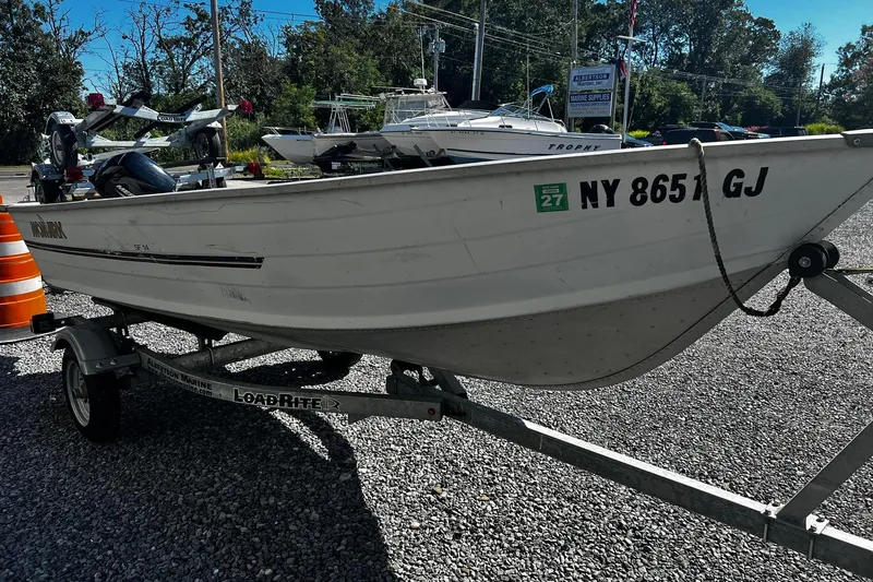 Slide: The Image of 1997 Monark SF 14 S boat on trailer, parked on gravel lot with other boats. - 3