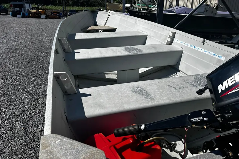 Slide: The Image of 1997 Monark SF 14 S aluminum boat with outboard motor, parked on gravel. - 4