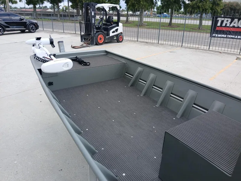 Slide: The Image of 2000 Southfork 16 CC boat with spacious deck, parked near a forklift and car. - 5