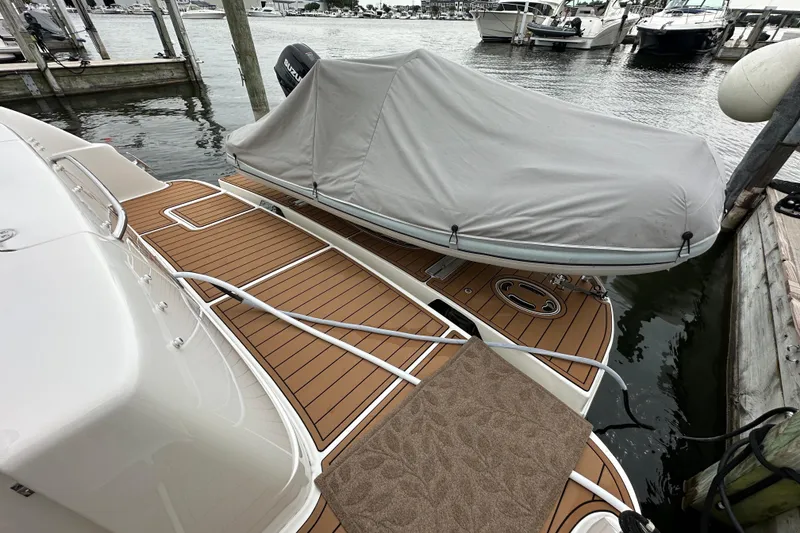 Slide: The Image of 2004 Sea Ray 420 Sedan Bridge with covered dinghy at marina dock. - 2