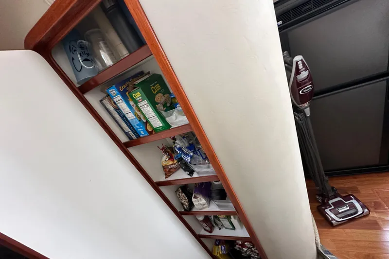 Slide: The Image of Storage shelves with snacks and cleaning supplies on a 2004 Sea Ray 420 Sedan Bridge. - 25