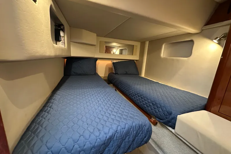 Slide: The Image of 2004 Sea Ray 420 Sedan Bridge cabin with twin beds and blue bedding. - 29
