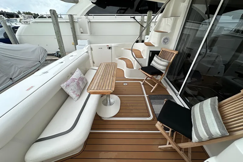 Slide: The Image of 2004 Sea Ray 420 Sedan Bridge yacht deck with seating and wooden table. - 4