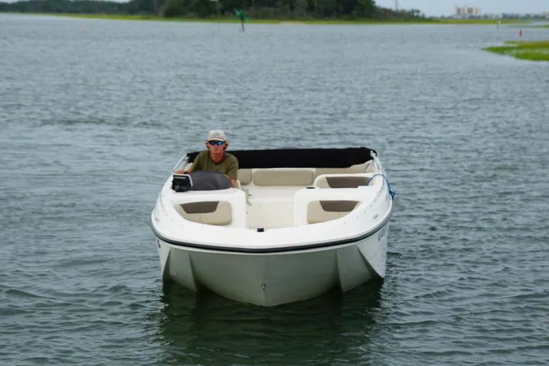 Slide: The Image of 2017 Bayliner Element F21 boat on calm water with a person at the helm. - 12