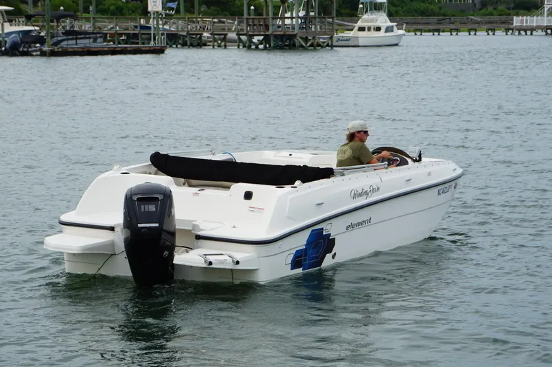 Slide: The Image of 2017 Bayliner Element F21 boat cruising on a calm lake with a person steering. - 13