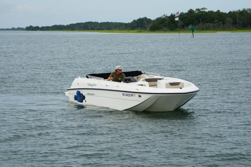 Slide: The Image of 2017 Bayliner Element F21 boat cruising on a calm lake with a person onboard. - 5