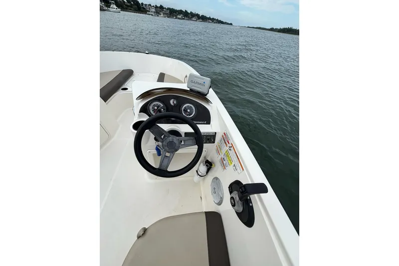 Slide: The Image of 2017 Bayliner Element F21 boat dashboard with steering wheel and controls on open water. - 8
