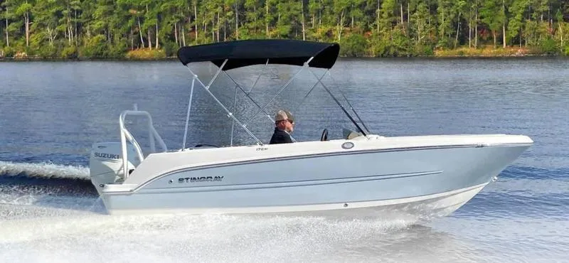 The Image of 2022 Stingray 172SC boat cruising on a lake with a forested background. - 1