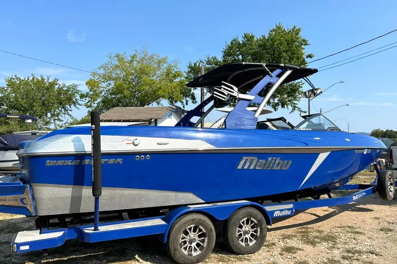 Slide: The Image of 2017 Malibu Wakesetter 25 LSV boat in vibrant blue on a trailer, outdoors. - 13
