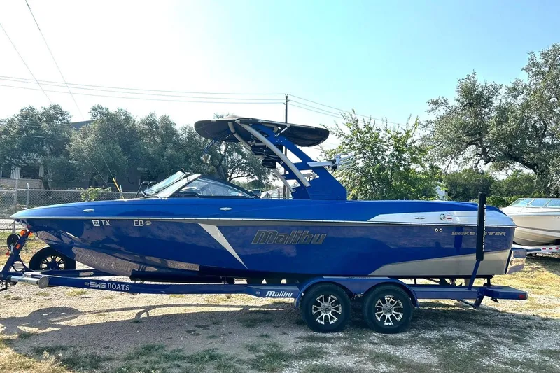 Slide: The Image of 2017 Malibu Wakesetter 25 LSV boat in vibrant blue on trailer, parked outdoors. - 17