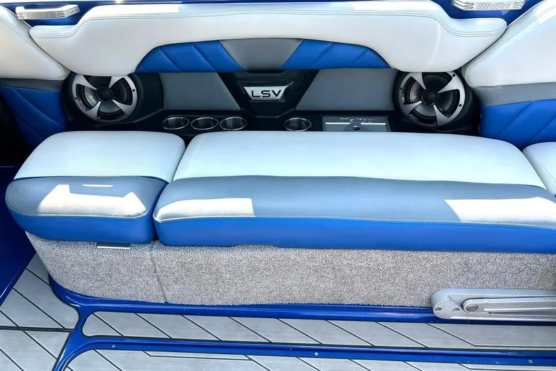 Slide: The Image of 2017 Malibu Wakesetter 25 LSV interior seating with blue and gray upholstery, featuring cup holders and speakers. - 33