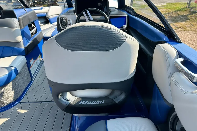 Slide: The Image of 2017 Malibu Wakesetter 25 LSV interior with blue and gray seating, steering wheel, and dashboard. - 46