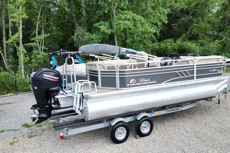 Slide: The Image of 2020 Sun Tracker Party Barge 20 DLX pontoon boat on trailer, surrounded by trees. - 4