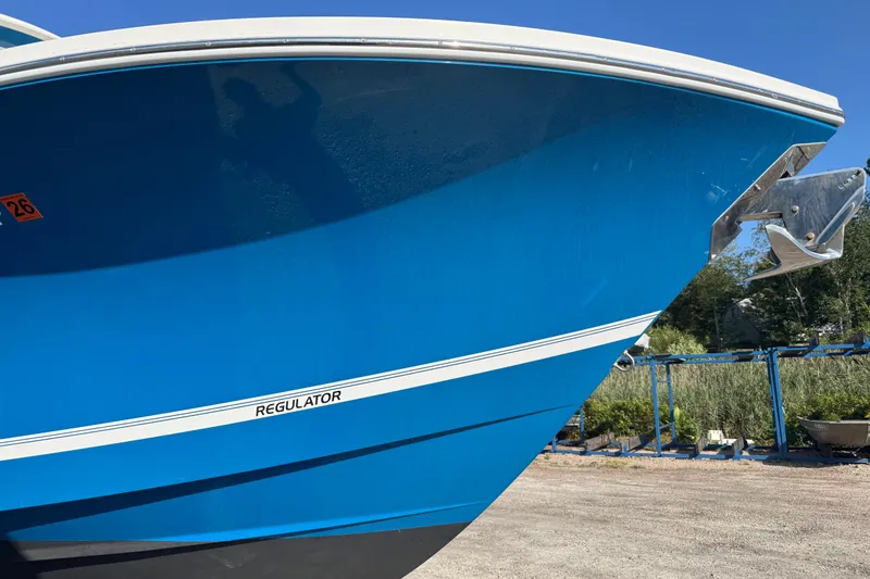 Slide: The Image of 2017 Regulator 28 boat with blue hull and anchor, parked outdoors. - 11