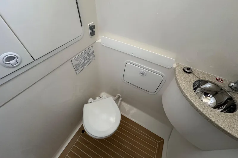 Slide: The Image of 2017 Regulator 28 boat bathroom with toilet, sink, and storage cabinet. - 31