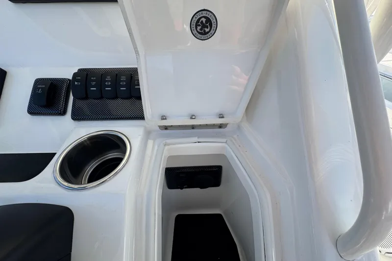 Slide: The Image of 2017 Regulator 28 boat console with open storage compartment and control switches. - 43