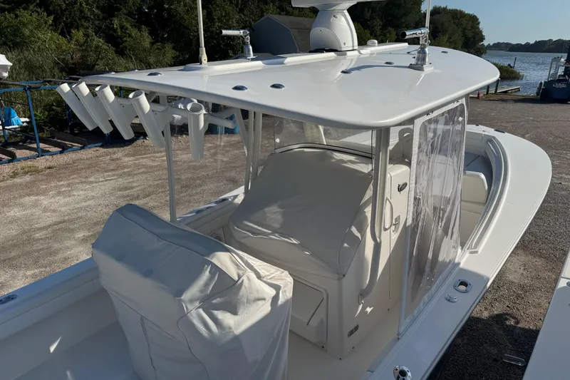 Slide: The Image of 2017 Regulator 28 boat with covered seating and fishing rod holders, docked near water. - 55
