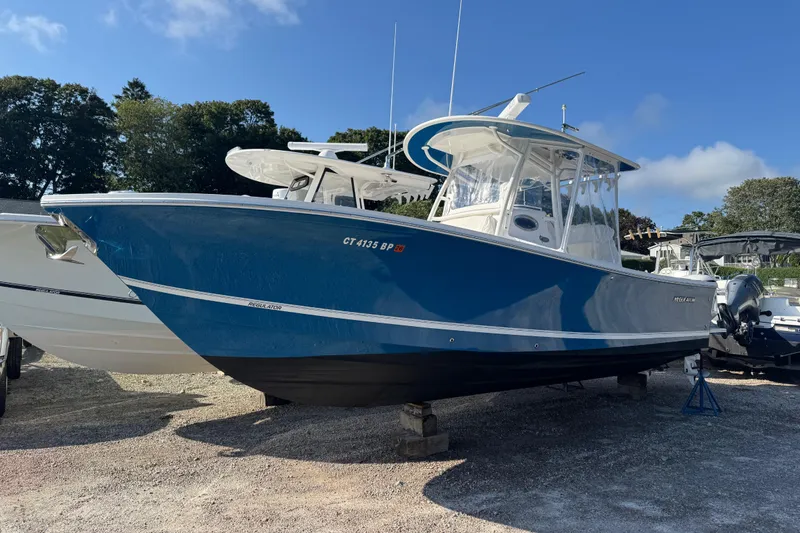 Slide: The Image of 2017 Regulator 28 boat in blue, parked on gravel with trees in background. - 9