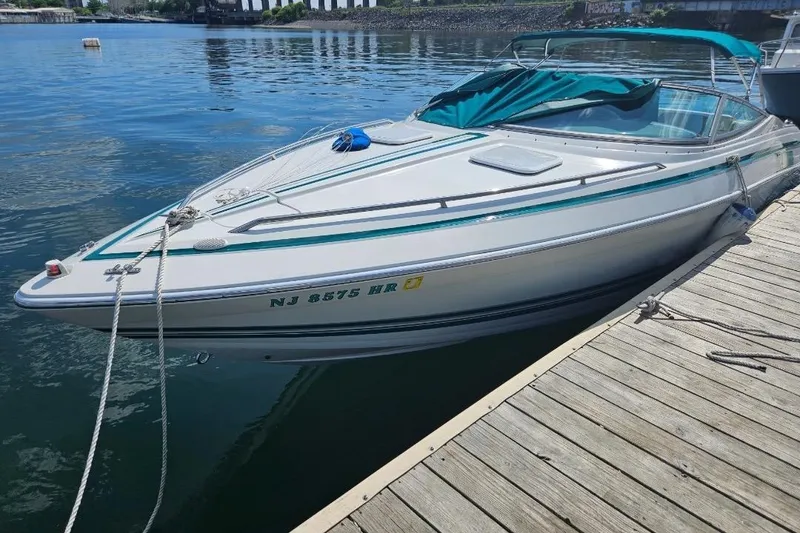 Slide: The Image of 1998 Formula 252 SS boat docked on calm water, featuring teal accents and a covered bow. - 8