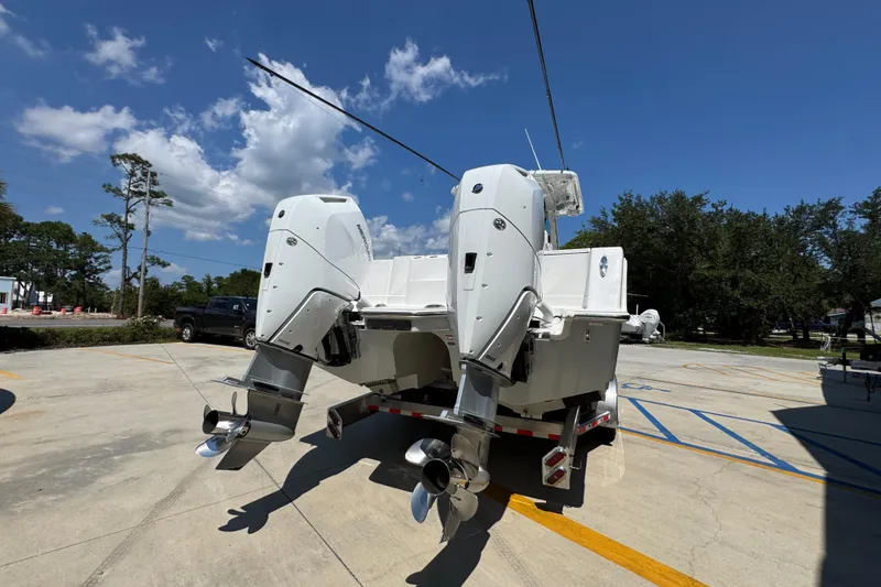 Slide: The Image of 2025 Caymas 34 CT boat with dual outboard motors in a sunny parking lot. - 14