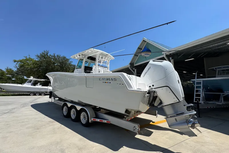 Slide: The Image of 2025 Caymas 34 CT boat on trailer, featuring dual Mercury engines, parked outdoors. - 17