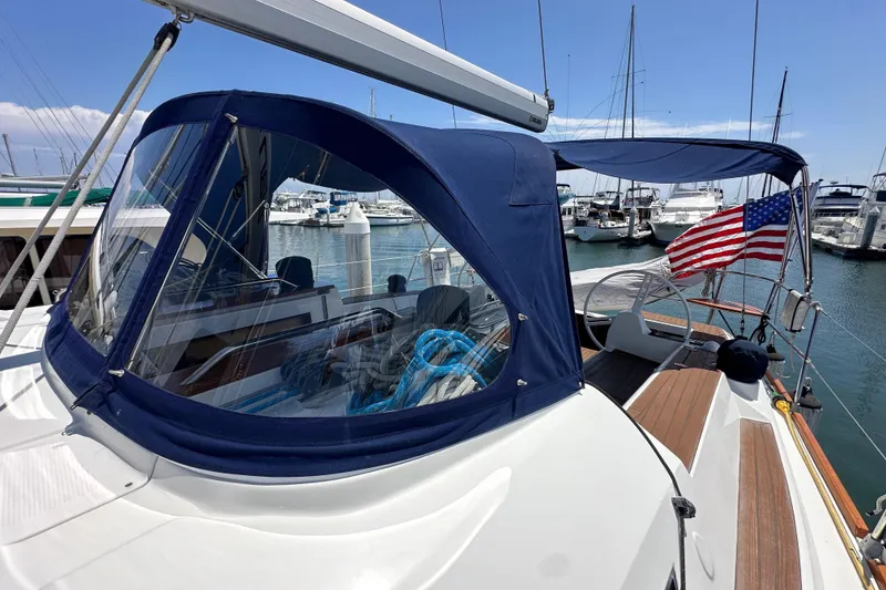 Slide: The Image of 2018 Elan 45 Impressions yacht with blue canopy and American flag in marina. - 22