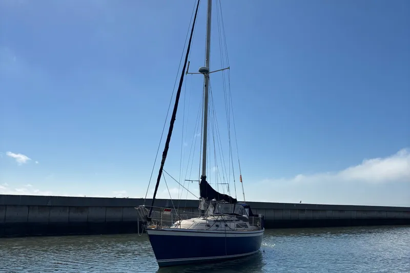 Slide: The Image of 1981 O'Day 34 sailboat docked in calm waters under a clear blue sky. - 4