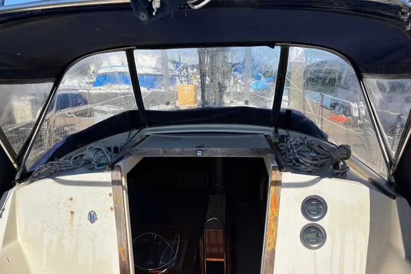 Slide: The Image of 1981 O'Day 34 sailboat cockpit with ropes and gauges, marina view through windows. - 9
