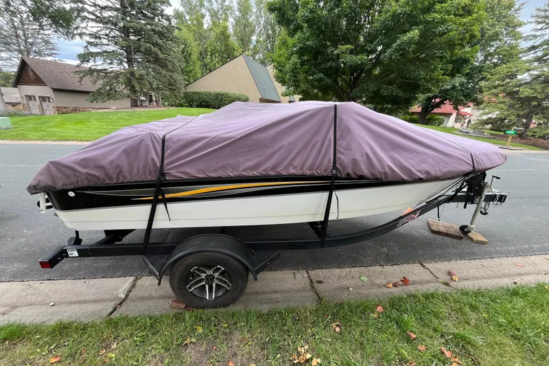 Slide: The Image of 2008 Four Winns H180 boat covered on a trailer, parked on a suburban street. - 24