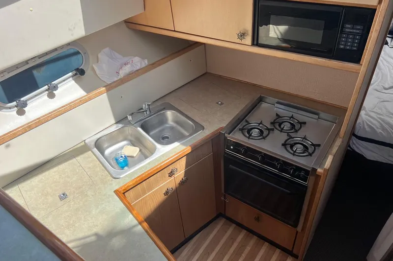 Slide: The Image of Compact kitchen in 2000 Bayliner 3388 Command Bridge Motoryacht with stove, sink, and microwave. - 19