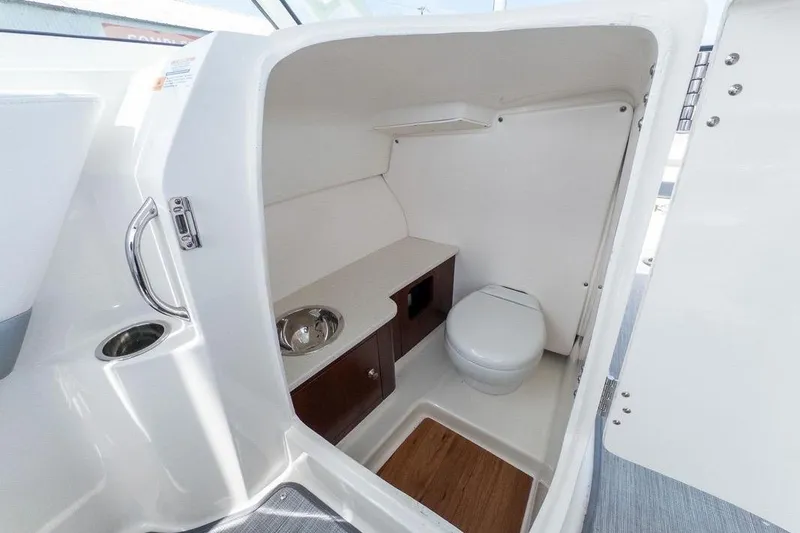 Slide: The Image of 2021 Robalo R247 Dual Console boat interior with compact bathroom and sink. - 11