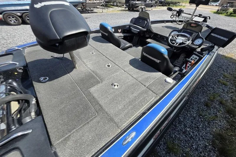Slide: The Image of 2012 Phoenix 721 ProXP boat interior with seating and control panel, parked on gravel. - 6