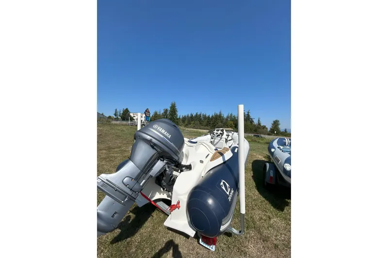 Slide: The Image of 2016 Zodiac Yachtline 420 with Yamaha motor on grassy field under clear blue sky. - 5