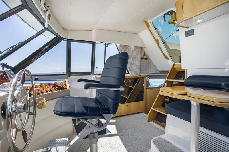 Slide: The Image of Interior of 1997 Bayliner 4788 Pilot House Motoryacht with helm, seating, and wooden accents. - 24