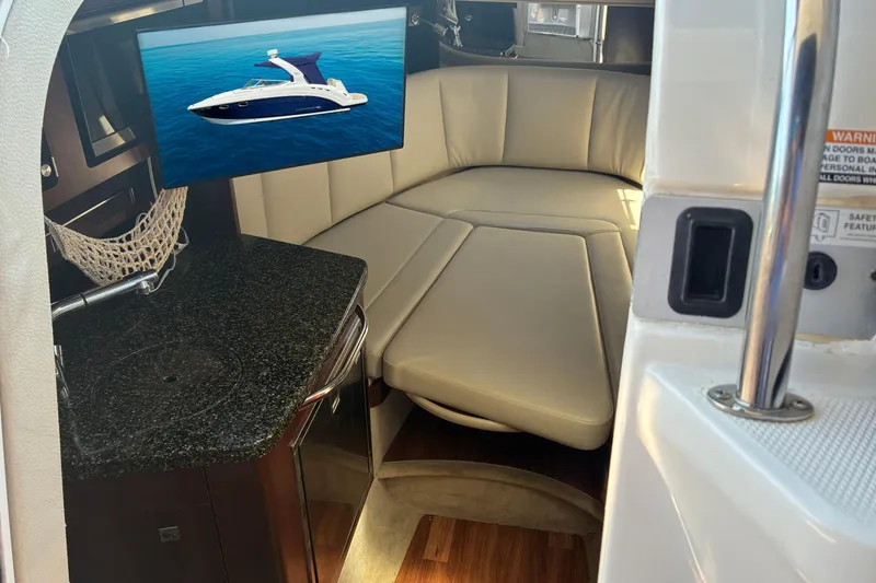 Slide: The Image of 2018 Chaparral 270 Signature cabin interior with seating and kitchenette. - 14