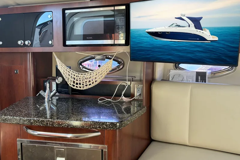 Slide: The Image of Interior of 2018 Chaparral 270 Signature boat with kitchenette and TV display. - 16