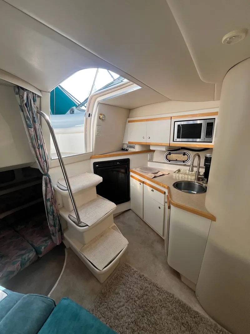 Slide: The Image of Interior of 1996 Cruisers Yachts 3375, featuring compact kitchen and stairs. - 12