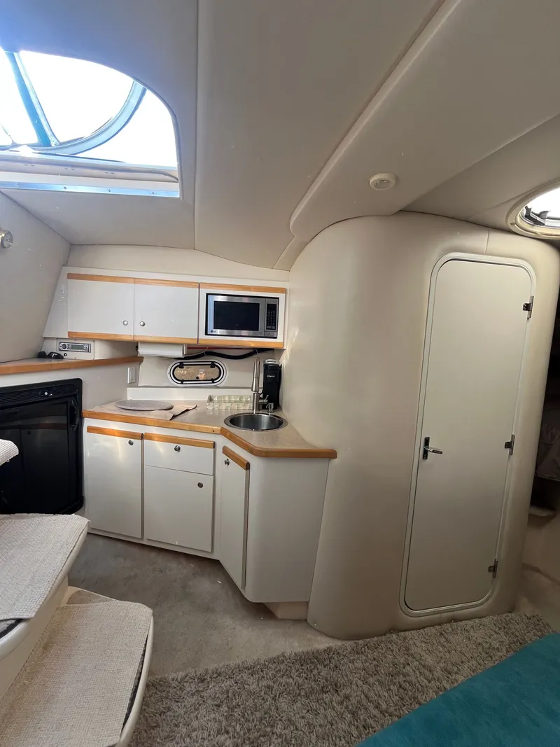 Slide: The Image of Interior of 1996 Cruisers Yachts 3375, featuring a compact kitchen with modern amenities. - 13
