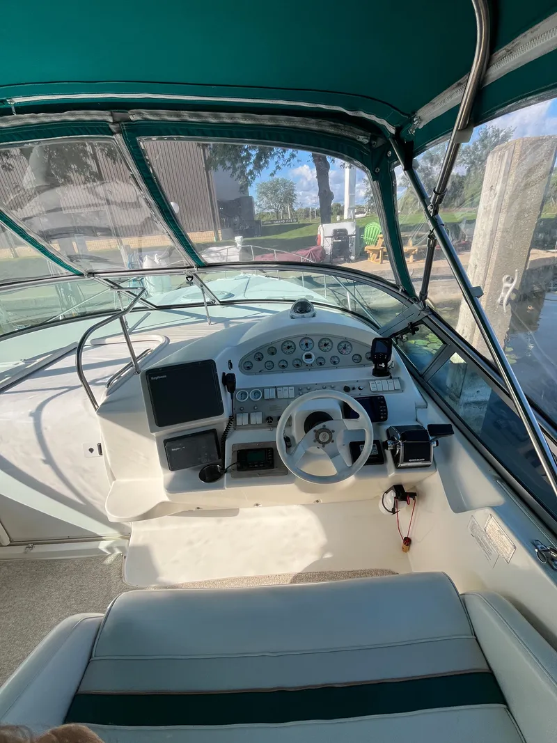 Slide: The Image of 1996 Cruisers Yachts 3375 helm with steering wheel and instrument panel under green canopy. - 5