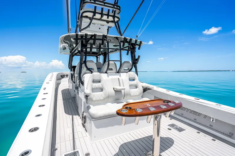 Slide: The Image of 2024 Freeman 42 boat interior with luxurious seating and fishing rod holders on calm blue water. - 31