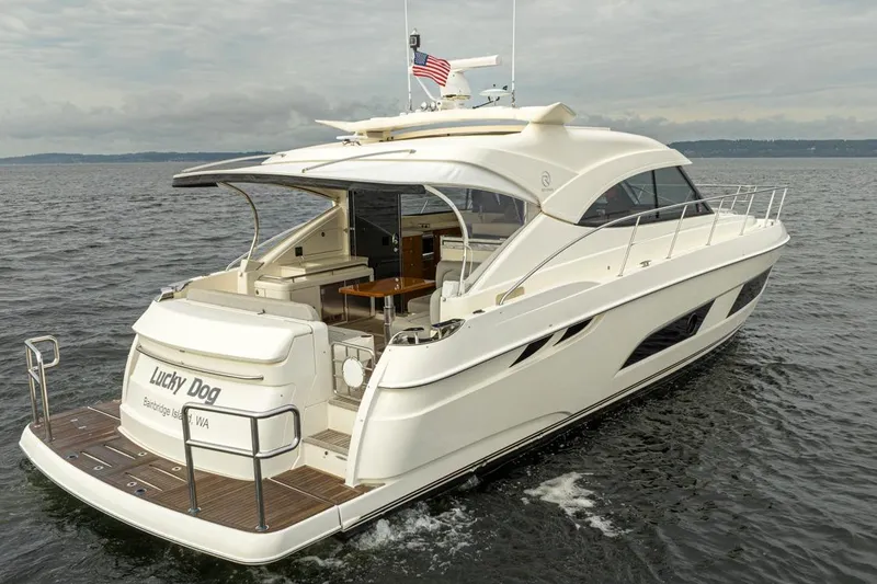 The Image of 2018 Riviera 4800 Sport Yacht cruising on open water, rear view. - 0