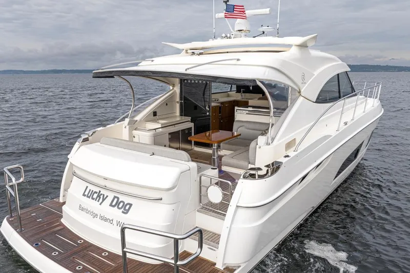 Slide: The Image of 2018 Riviera 4800 Sport Yacht on water, rear view, "Lucky Dog" name visible. - 1