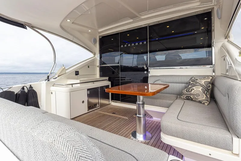 Slide: The Image of 2018 Riviera 4800 Sport Yacht interior with elegant seating and wooden table, overlooking the ocean. - 20